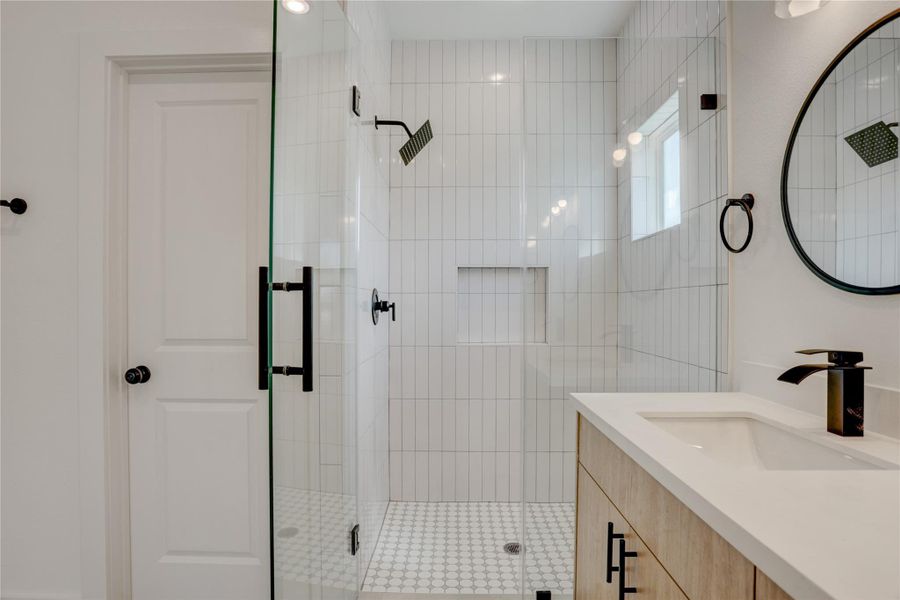 The primary bath has a frameless standing shower with subway tile surround.