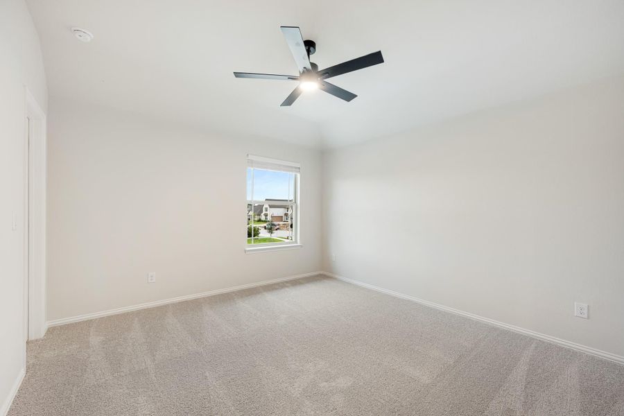 Empty bedroom with beige carpet, ceiling fan, and single window with neighborhood view Empty bedroom with beige carpet, ceiling fan, and single window with neighborhood view