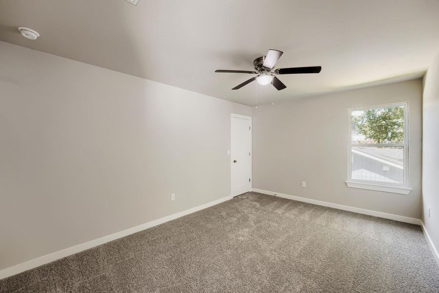 A well-lit bedroom offering plush carpeting and a modern ceiling fan for ultimate comfort. A well-lit bedroom offering plush carpeting and a modern ceiling fan for ultimate comfort.