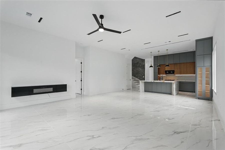 Unfurnished living room featuring a ceiling fan and light marble finish floors Unfurnished living room featuring a ceiling fan and light marble finish floors