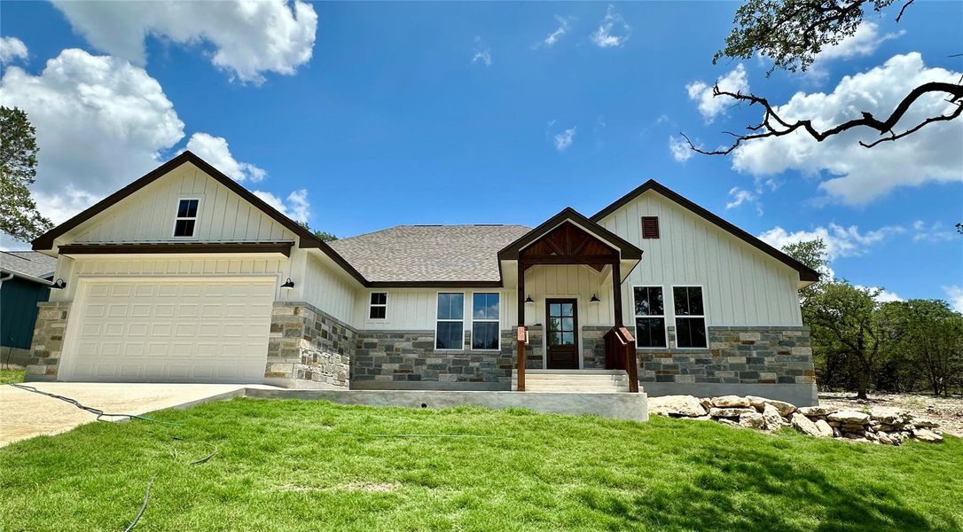 Modern farmhouse featuring stone siding, a front lawn, board and batten siding, concrete driveway, and a garage Modern farmhouse featuring stone siding, a front lawn, board and batten siding, concrete driveway, and a garage