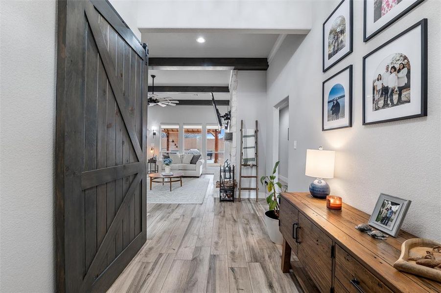 Corridor featuring light hardwood / wood-style flooring, a barn door, and beamed ceiling