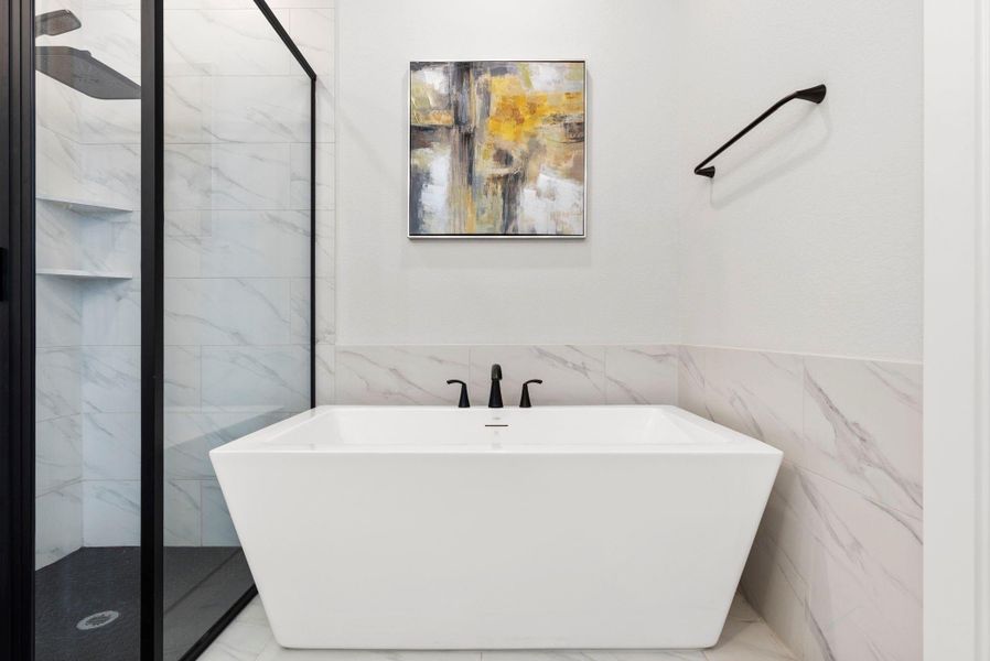 Spa-inspired bathroom with freestanding soaking tub, marble-look tile surrounds, and sleek matte-black fixtures.