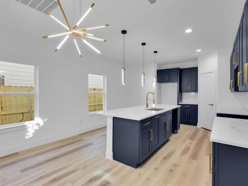 Kitchen featuring light hardwood / wood-style flooring, blue cabinets, hanging light fixtures, and sink