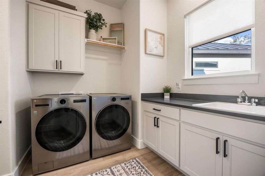 Washroom featuring cabinets, sink, washer and dryer, and light wood-type flooring Washroom featuring cabinets, sink, washer and dryer, and light wood-type flooring