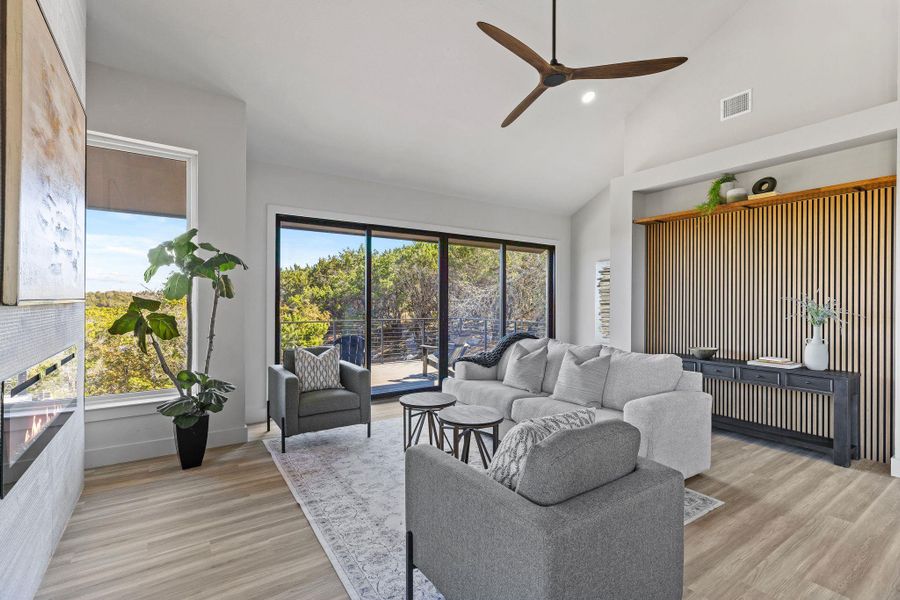 Living room featuring baseboards, visible vents, light wood finished floors, high vaulted ceiling, and ceiling fan