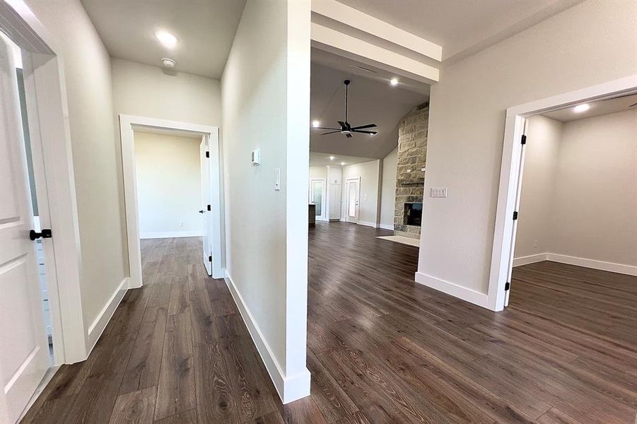 Hallway featuring vaulted ceiling, dark flooring, and recessed lighting