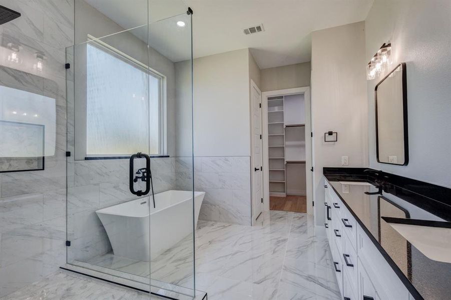 Freestanding soaking tub within a glass-enclosed shower featuring a rainfall showerhead