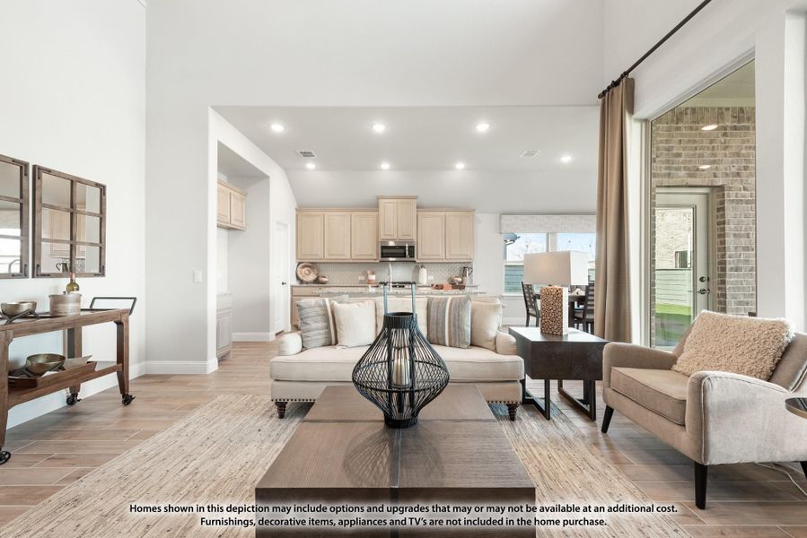 Open-concept living room with light wood floors, neutral sofa, and kitchen visible in background