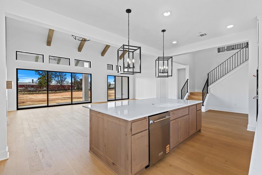 Kitchen featuring light wood-type flooring, a kitchen island, hanging lights, dishwasher, and open floor plan