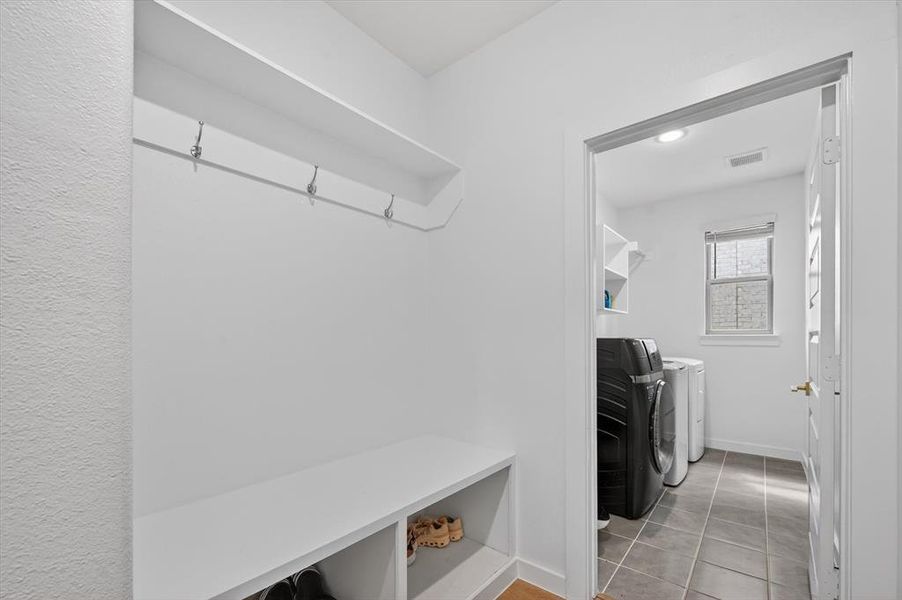 Entryway mudroom with built-in bench and shelving, featuring coat hooks and recessed storage