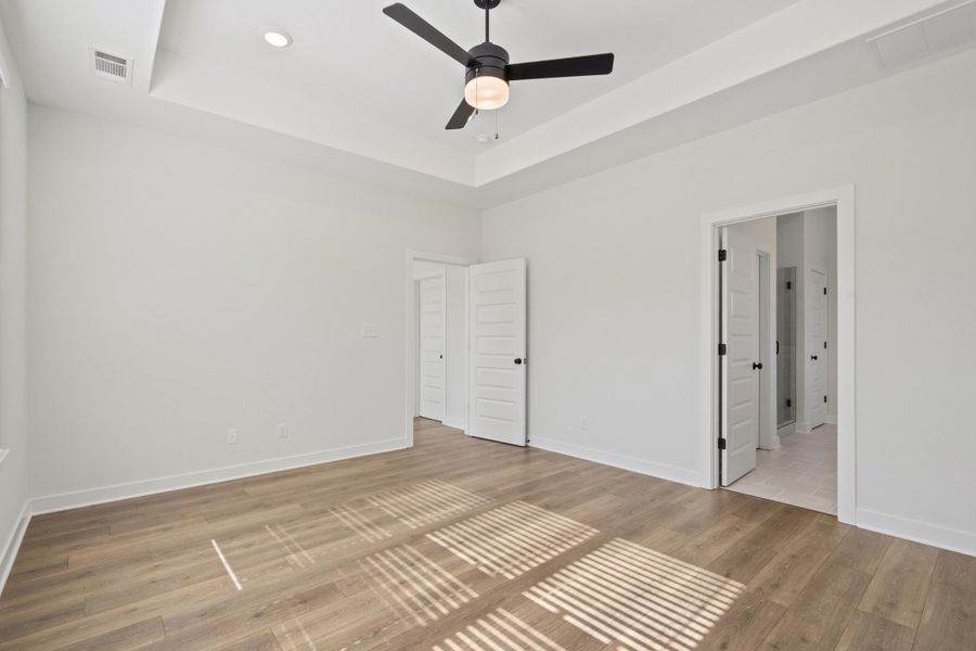 Tray ceiling with recessed lighting, wood-finish flooring, and a ceiling fan with integrated lighting Tray ceiling with recessed lighting, wood-finish flooring, and a ceiling fan with integrated lighting