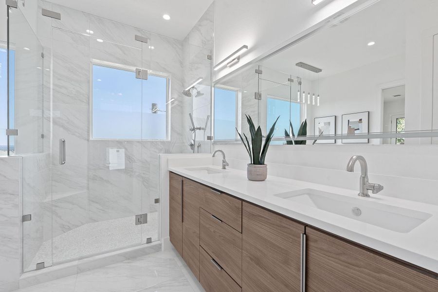 Spa-inspired ensuite with dual sinks, sleek wood cabinetry, and a seamless glass shower wrapped in tile. Custom cabinets. Spa-inspired ensuite with dual sinks, sleek wood cabinetry, and a seamless glass shower wrapped in tile. Custom cabinets.