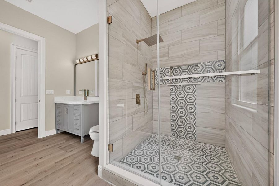 Elegant tilework highlights a glass-enclosed walk-in shower adjacent to a modern vanity area.