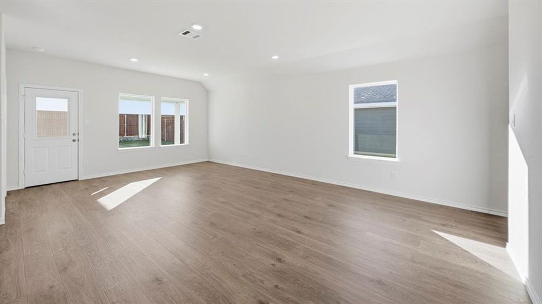 Empty room with light wood finished floors, vaulted ceiling, and recessed lighting Empty room with light wood finished floors, vaulted ceiling, and recessed lighting