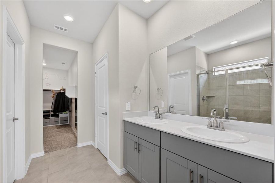 Full bath featuring double vanity, a walk in closet, a stall shower, light tile patterned floors, and recessed lighting