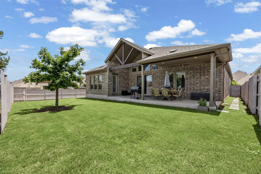 A well-maintained lawn stretches to a brick residence with a covered patio, perfect for outdoor enjoyment. A well-maintained lawn stretches to a brick residence with a covered patio, perfect for outdoor enjoyment.