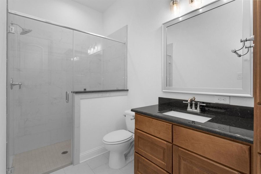 Another en-suite bathroom with a frameless glass walk-in shower, granite vanity, and warm wood cabinetry. Another en-suite bathroom with a frameless glass walk-in shower, granite vanity, and warm wood cabinetry.