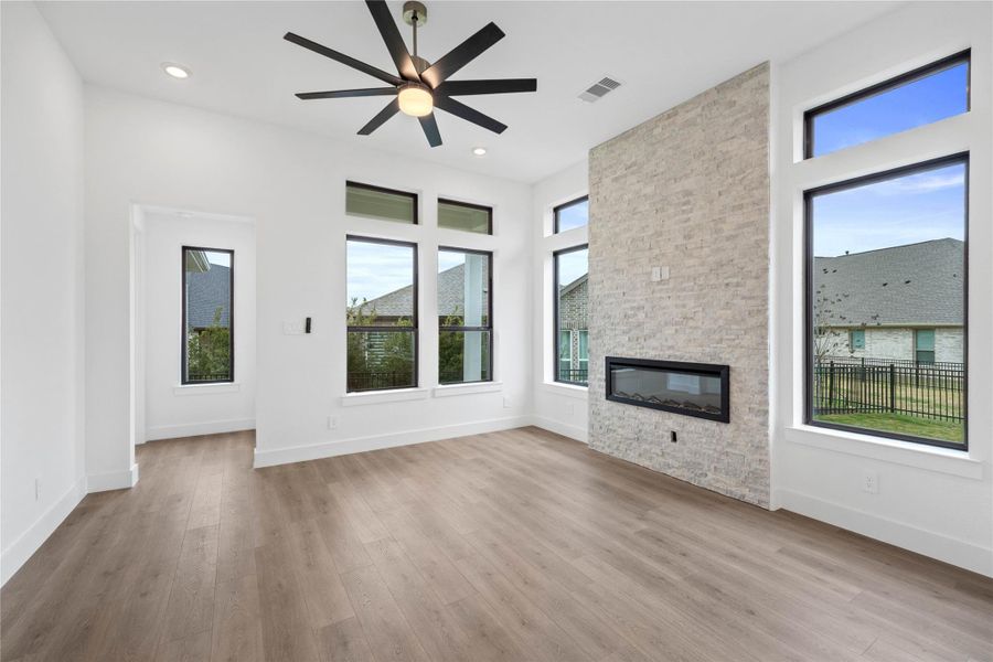 A grand great room with tall ceilings, ceiling fan, gorgeous fireplace with tile surround, abundant natural light, and an open, inviting ambiance--perfect for gatherings, relaxation, and making memories.