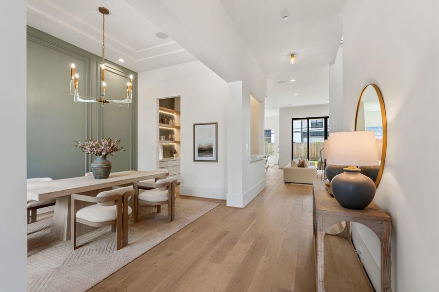 Moving through the foyer, the formal dining space opens with 12-foot ceilings, wide-plank white oak flooring, and elegant wall detailing. The open flow leads seamlessly toward the main living areas.