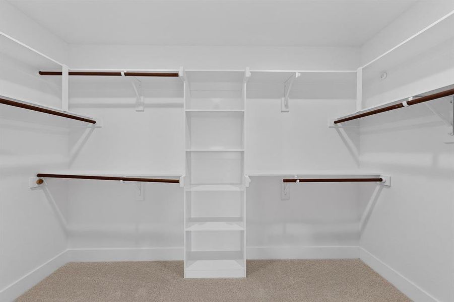 Walk-in closet featuring built-in shelving, multiple hanging rods, and neutral-toned carpeting