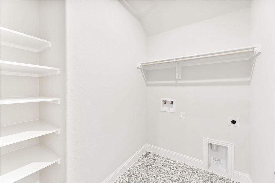 Laundry room with built-in shelving, wall-mounted drying rack, washer hookups, and patterned tile floor