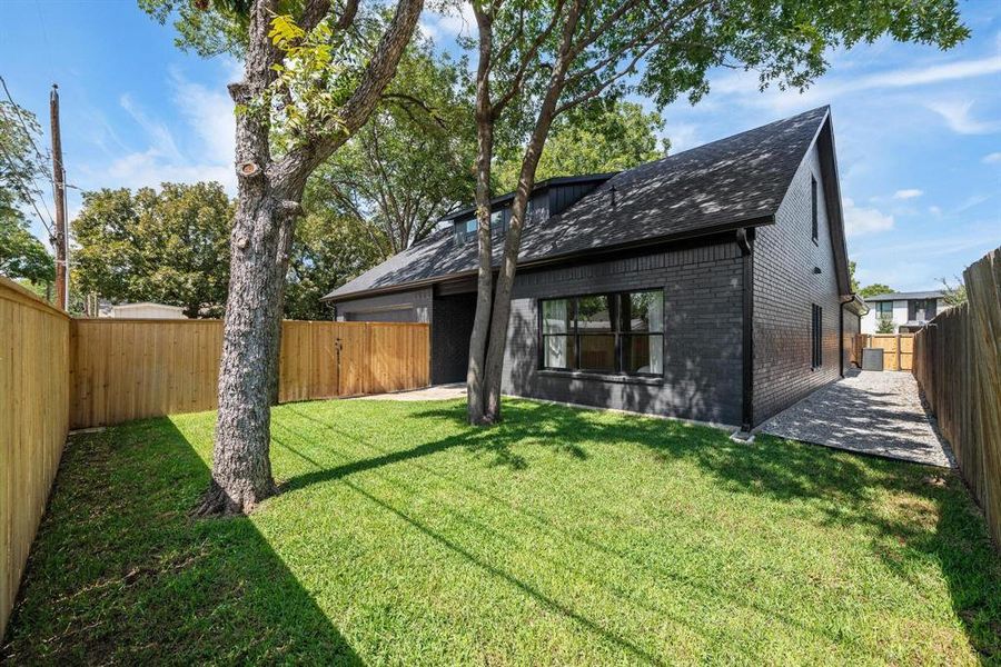 Back of property featuring brick siding, a fenced backyard, a shingled roof, and a patio Back of property featuring brick siding, a fenced backyard, a shingled roof, and a patio