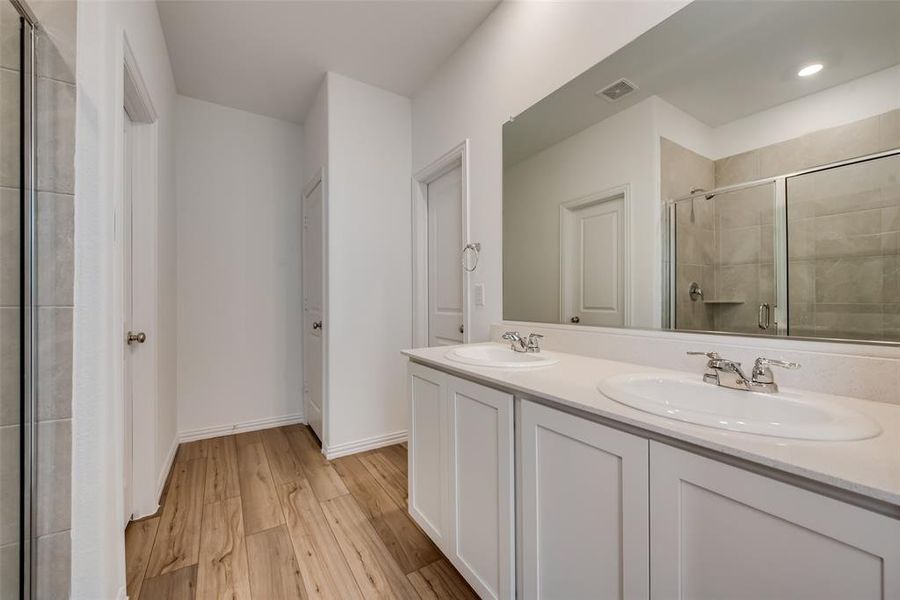 Bathroom with vanity with extensive cabinet space, walk in shower, hardwood / wood-style floors, and dual sinks