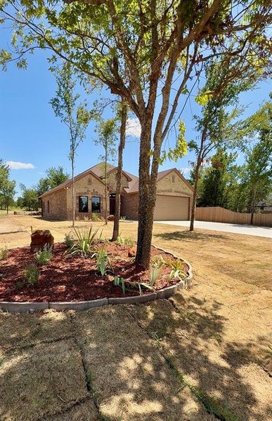 Additional personalized landscape in front yard, featuring stone pieces. Brick exterior with a two-car garage