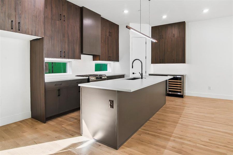 Kitchen featuring sink, light an island with sink, decorative light fixtures, and extractor fan