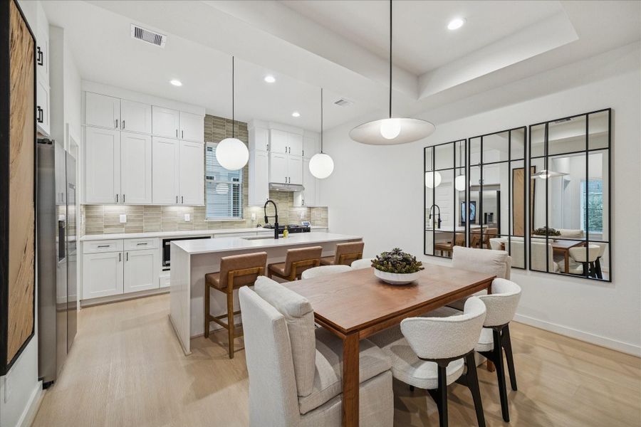 Sleek kitchen and dining area combine form and function with quartz countertops, stainless appliances, and pendant lighting that highlights the spacious island. Custom cabinetry and designer tile create a clean, contemporary backdrop for everyday living and entertaining.