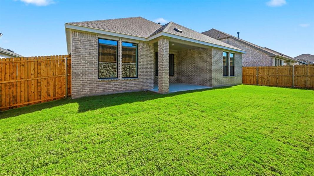 Back of property with a patio, a fenced backyard, brick siding, and roof with shingles Back of property with a patio, a fenced backyard, brick siding, and roof with shingles