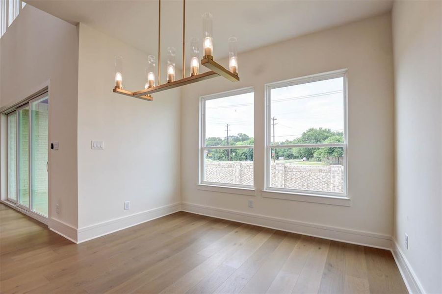 Unfurnished room with healthy amount of natural light, wood finished floors, and a chandelier