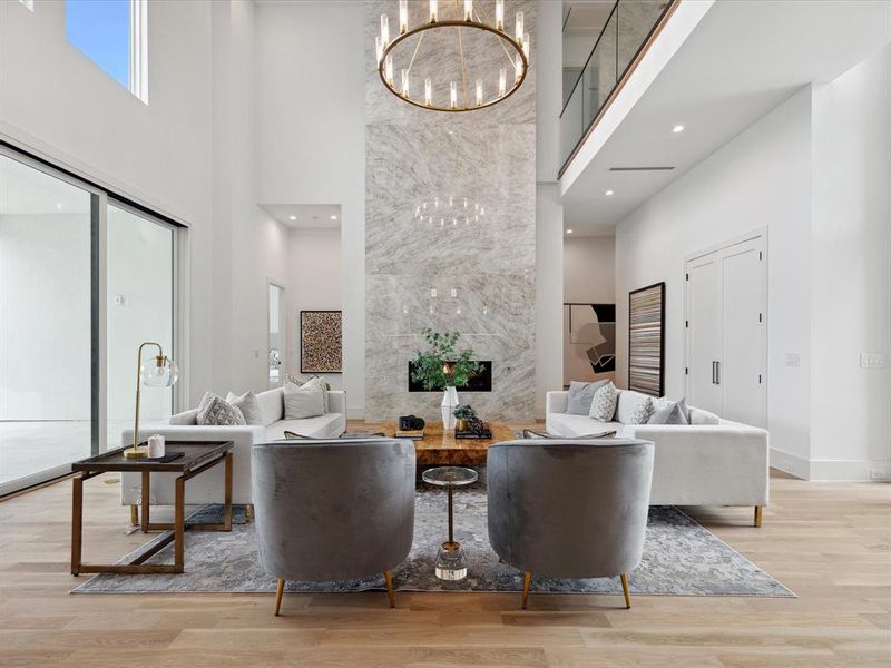 Living room featuring a towering ceiling, light hardwood / wood-style floors, and a chandelier