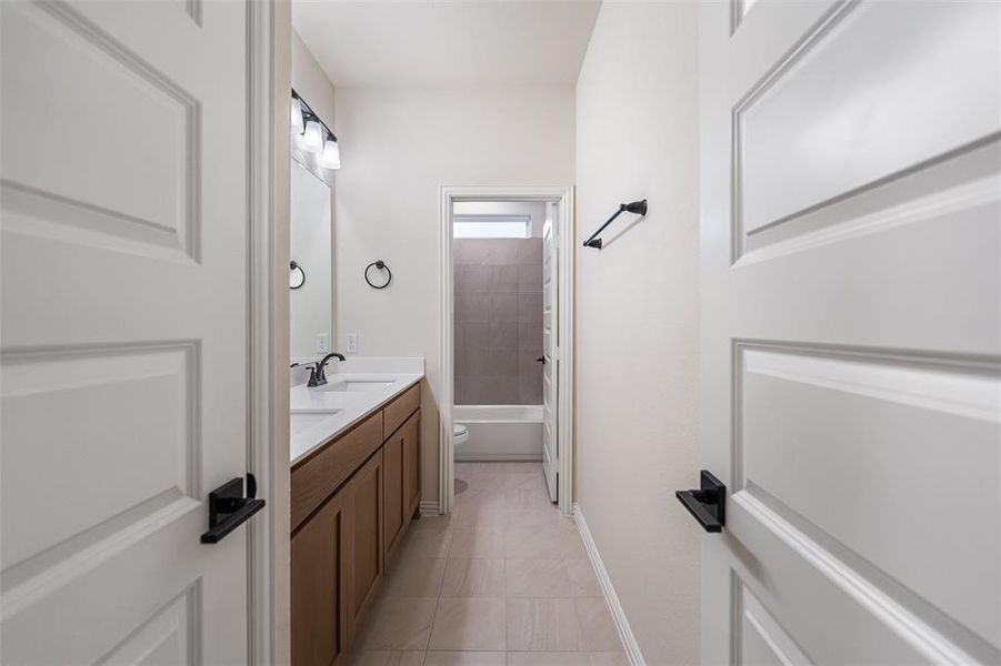 Full bathroom featuring double vanity, washtub / shower combination, and light tile patterned floors