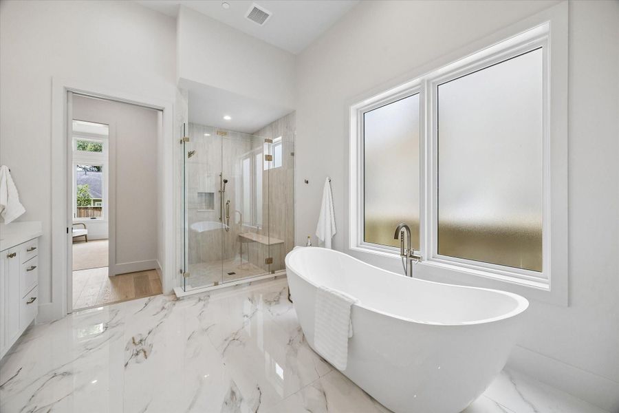 This angle highlights the freestanding tub and separate shower, bringing a spa-like feel to the first-floor primary bath. This angle highlights the freestanding tub and separate shower, bringing a spa-like feel to the first-floor primary bath.