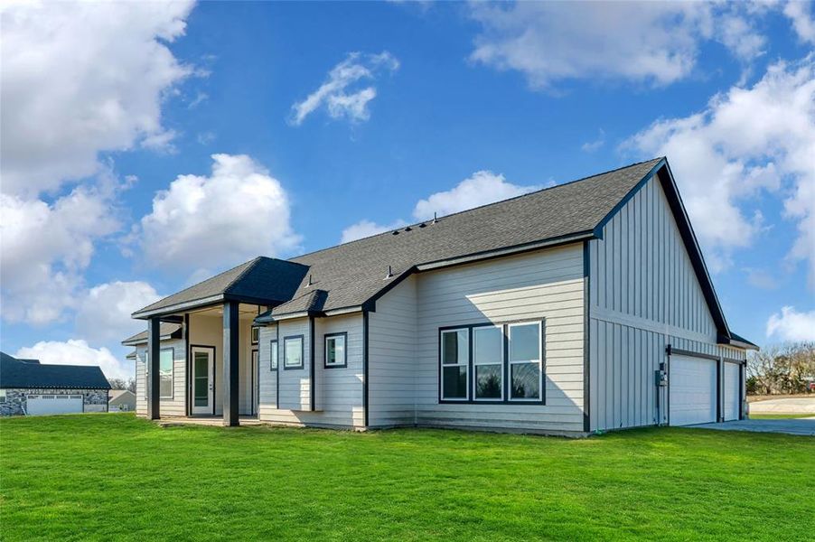 Rear view of house with a garage and a yard