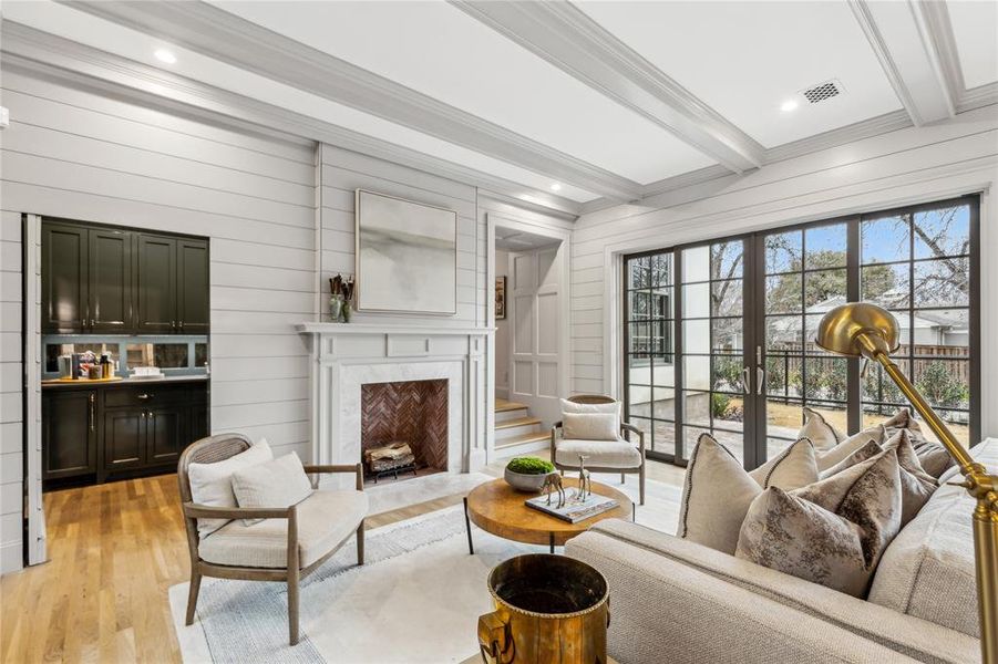 Living room with visible vents, ornamental molding, light wood-style floors, beam ceiling, and a high end fireplace