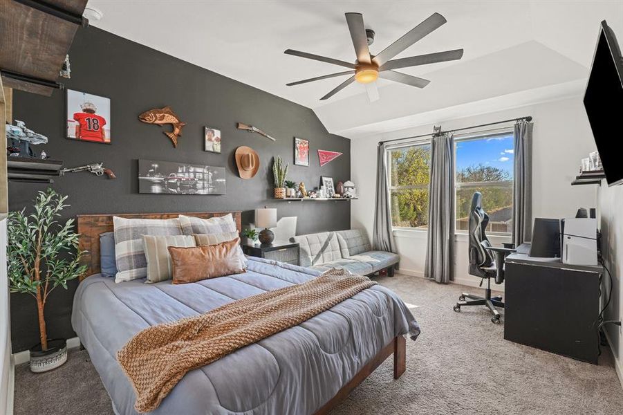Bedroom featuring an accent wall, a desk, carpet flooring, a ceiling fan, and lofted ceiling