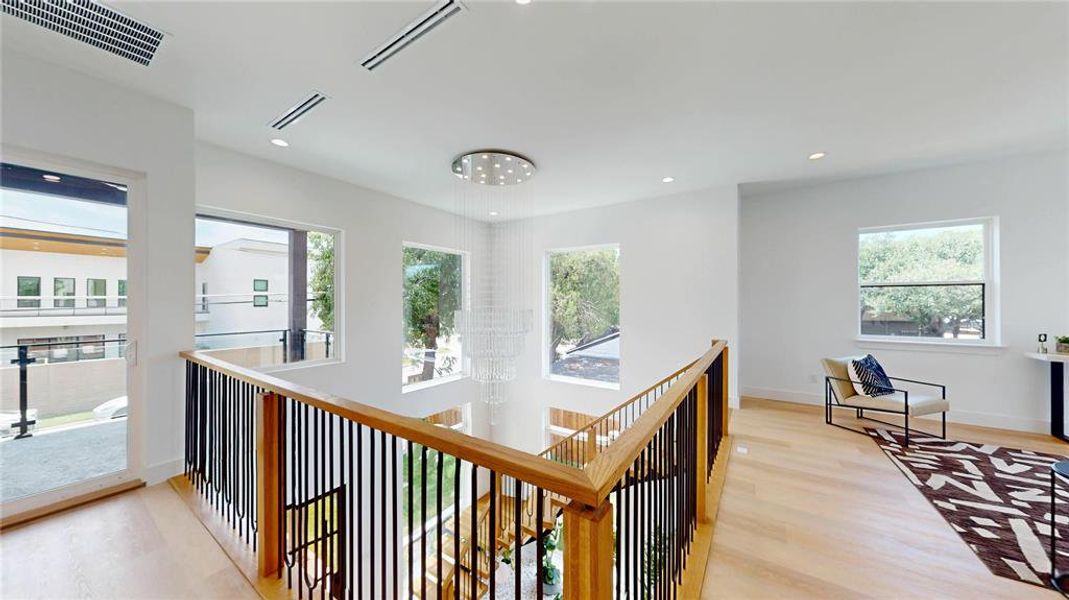 Hallway with light wood-style flooring, recessed lighting, a chandelier, and an upstairs landing