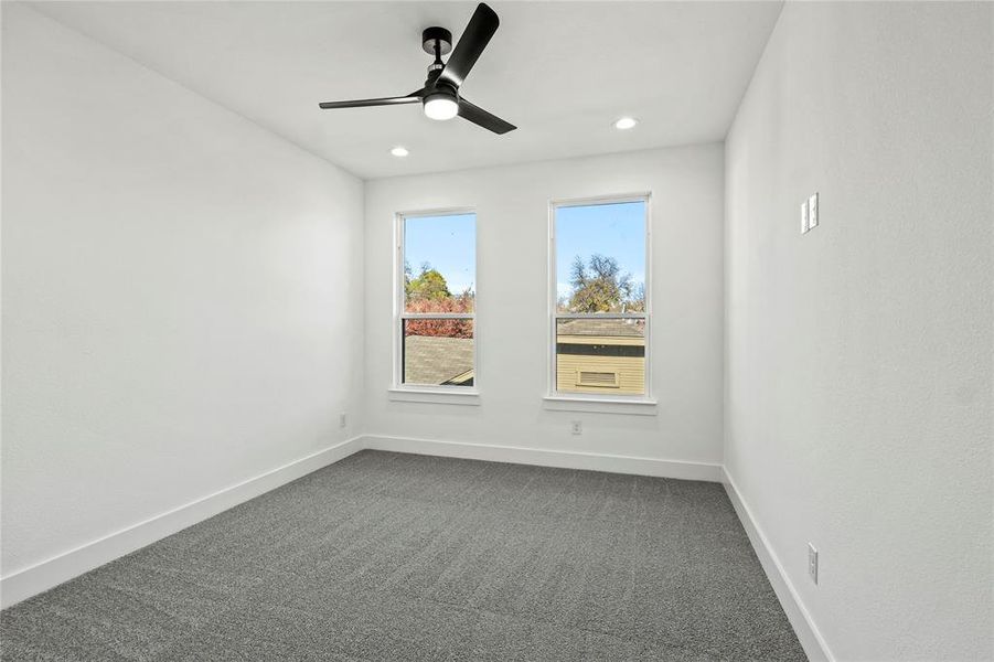 Carpeted spare room featuring ceiling fan