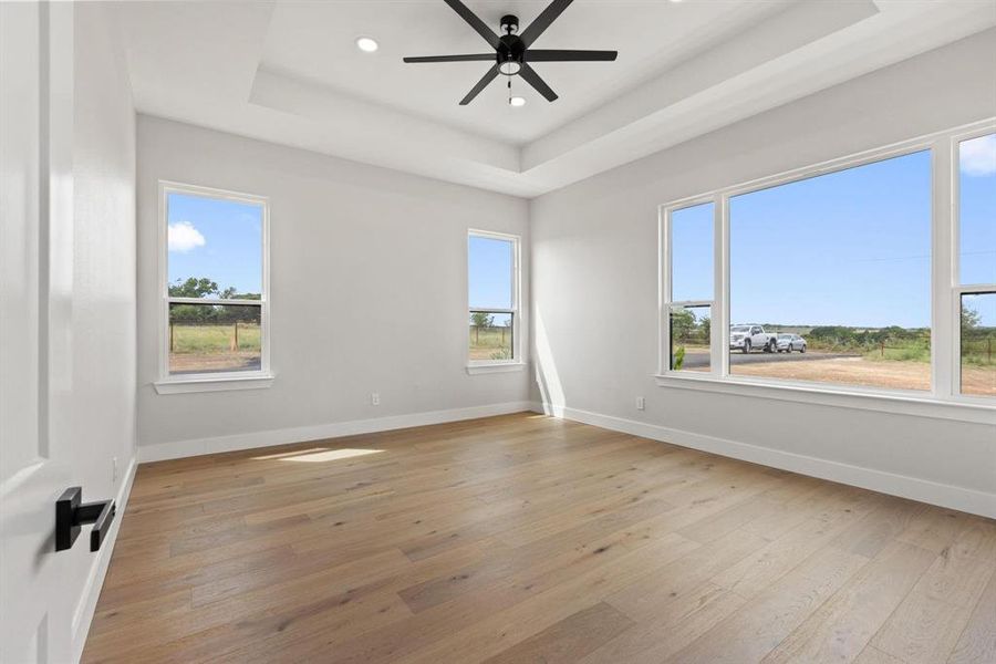 Spare room featuring a raised ceiling, light wood-
style flooring, recessed lighting, and a ceiling fan Spare room featuring a raised ceiling, light wood-
style flooring, recessed lighting, and a ceiling fan