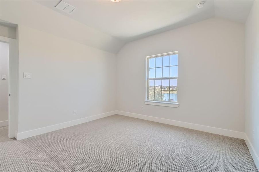 Carpeted spare room featuring a water view and vaulted ceiling