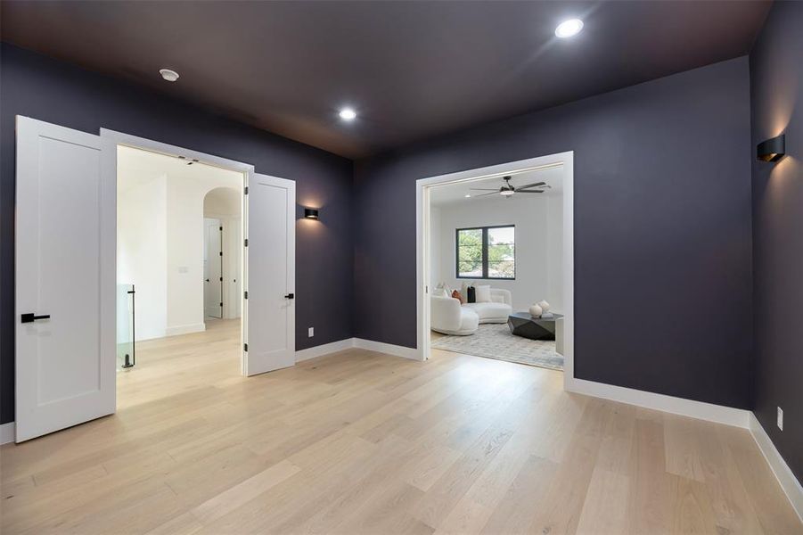 Empty room featuring light wood-style flooring, recessed lighting, a ceiling fan, and arched walkways Empty room featuring light wood-style flooring, recessed lighting, a ceiling fan, and arched walkways