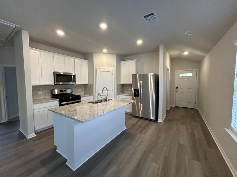 Kitchen with white cabinetry, stainless steel appliances, tasteful backsplash, light stone countertops, and recessed lighting Kitchen with white cabinetry, stainless steel appliances, tasteful backsplash, light stone countertops, and recessed lighting