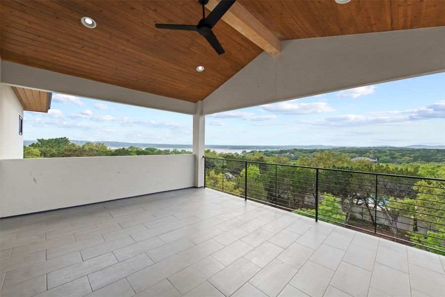 Photo is similar to patio on home being built. View of patio featuring a balcony, a wooded view, and ceiling fan.