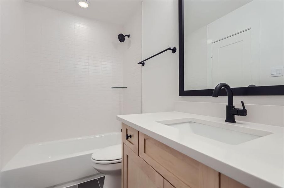 Full bathroom with tile patterned floors, tiled shower / bath, vanity, and toilet