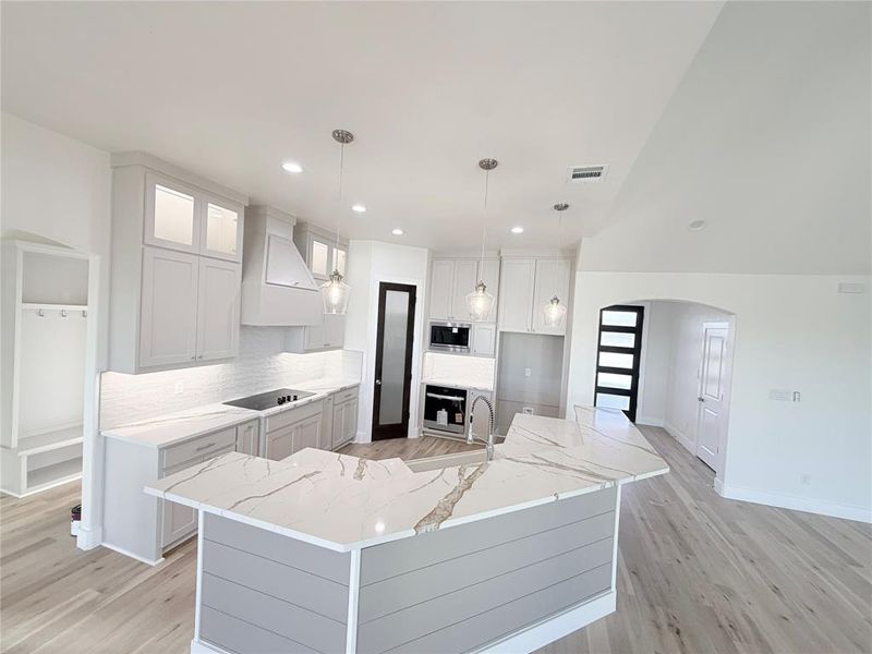 vinyl plank light wood-look flooring, quartz countertops with rich deep veining, and a large island vinyl plank light wood-look flooring, quartz countertops with rich deep veining, and a large island