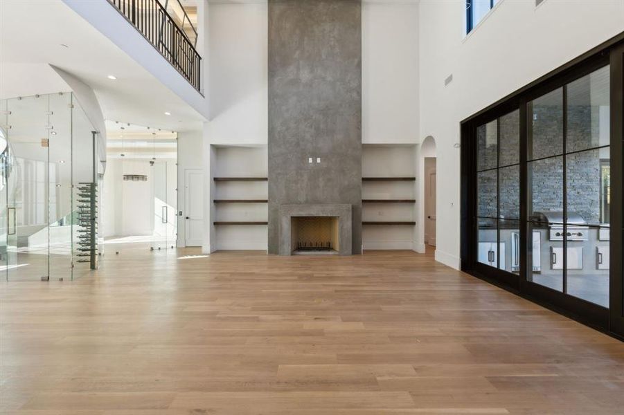 Unfurnished living room with a premium fireplace, light wood finished floors, a towering ceiling, and arched walkways