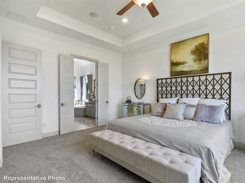 Carpeted bedroom featuring a tray ceiling, ensuite bath, a ceiling fan, and recessed lighting Carpeted bedroom featuring a tray ceiling, ensuite bath, a ceiling fan, and recessed lighting